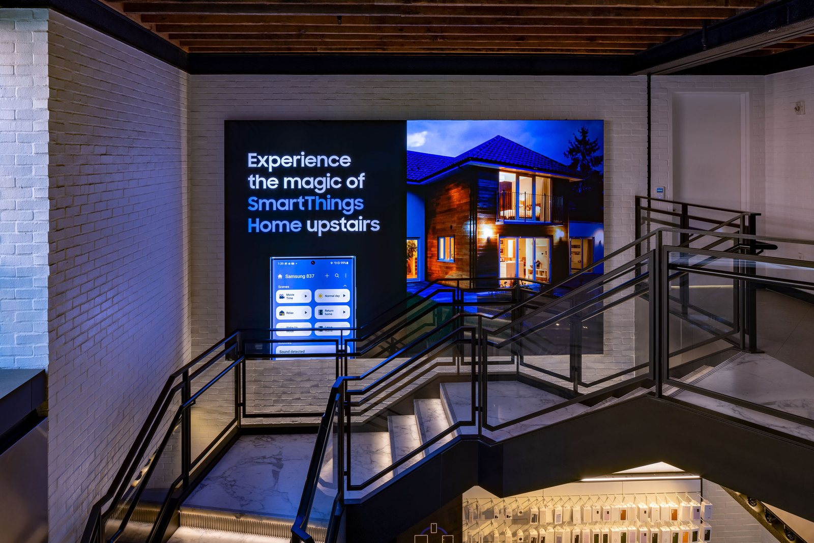 A staircase beside a wall screen reading Experience the magic of SmartThings Home upstairs.